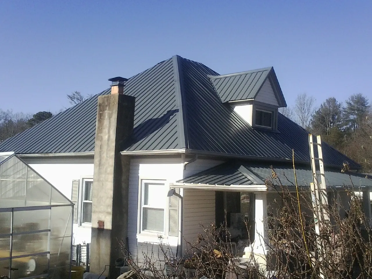 Dark blue standing seam metal roof on a white farmhouse with dormer — Slate & Tile Roof Repair by Roofing Brothers in West Elizabeth