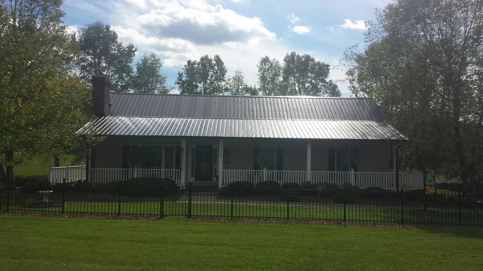 Gray metal roof on a brick ranch with a full width front porch — Gutter Guard Installation work by our crew in West Elizabeth
