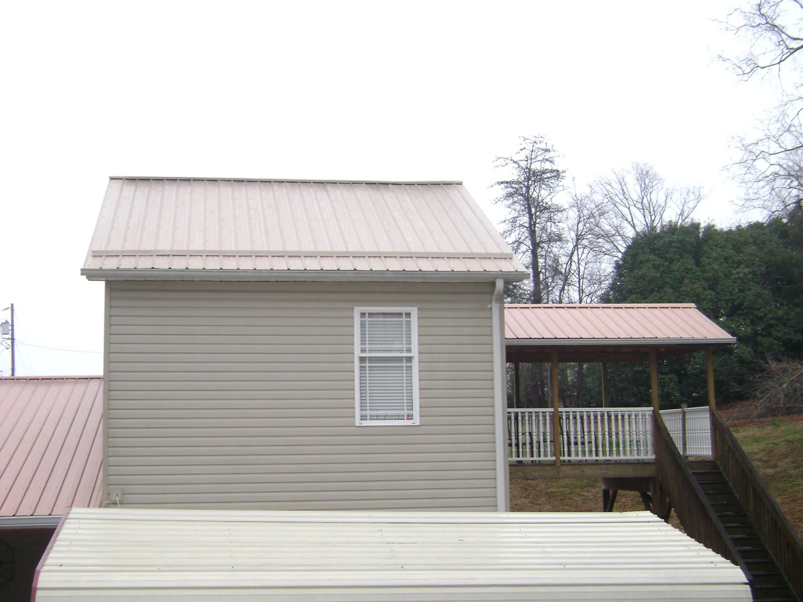 Tan metal roofs on a two story addition and attached porch, from a Roof Replacement job in West Elizabeth